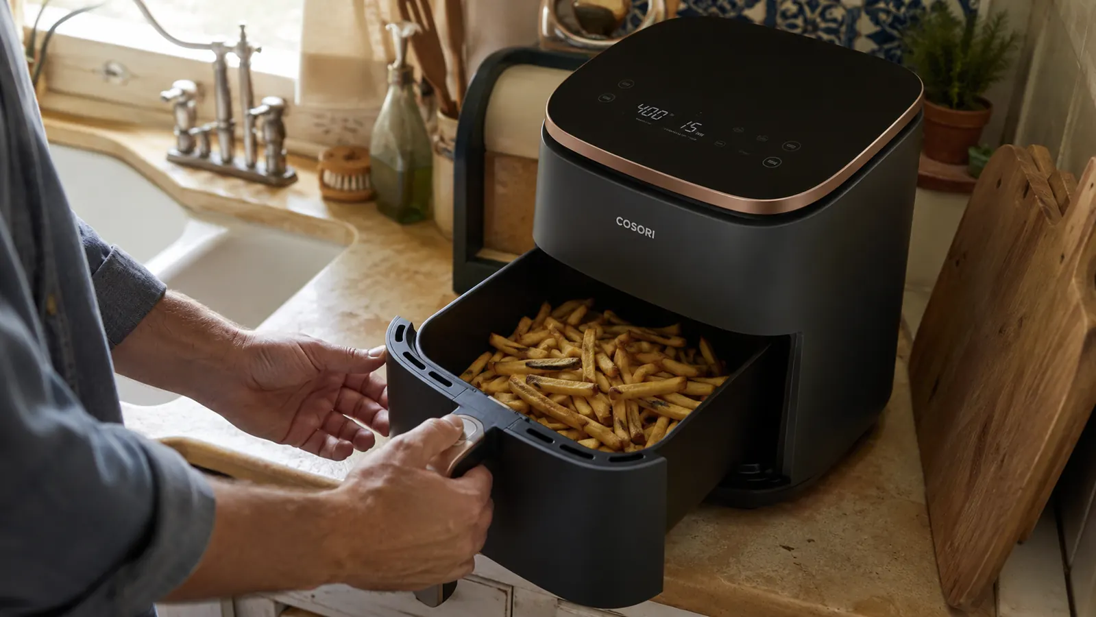Hands reaching for a basket of crispy fries just pulled from the Cosori Air Fryer Pro