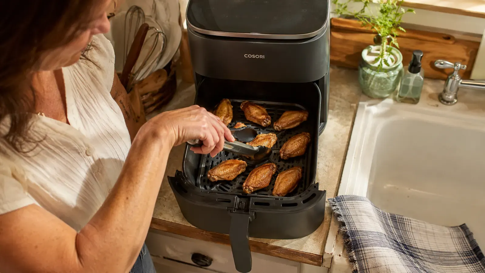 Overhead view into the Cosori Air Fryer Pro basket showing wings spaced in a single layer with gaps between pieces